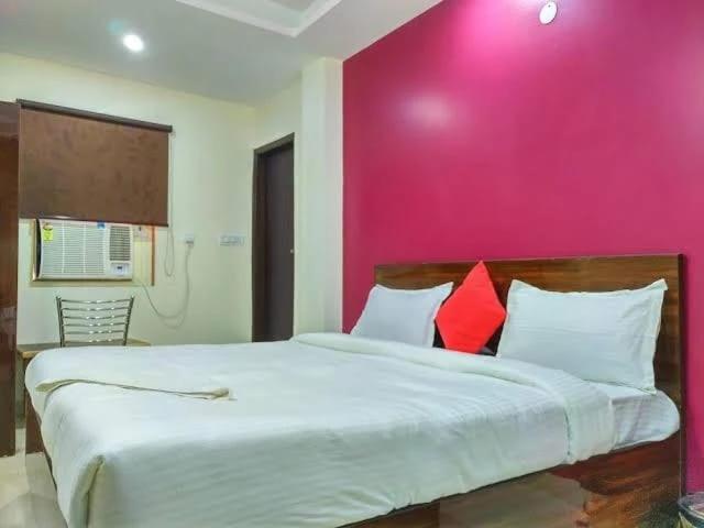 Un dormitorio con una pared rosa y una cama grande en HOTEL AIRPORT PALACE, en Nueva Delhi