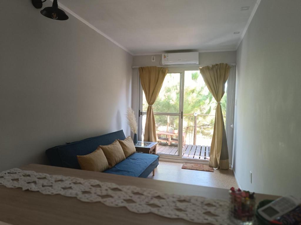 - un salon avec un canapé bleu et une grande fenêtre dans l'établissement Frente a la playa en El Pinar, à Ciudad de la Costa