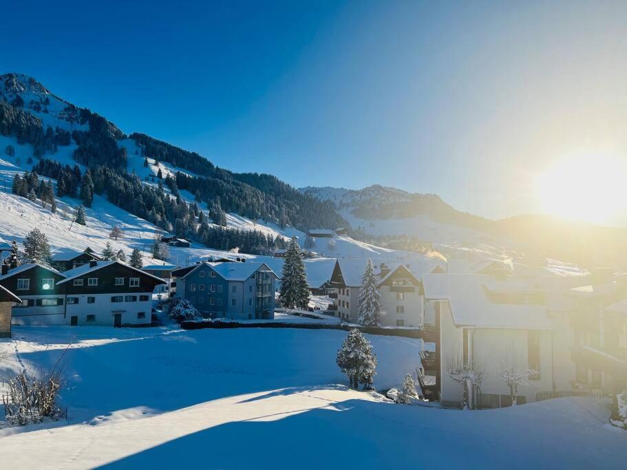 uma cidade coberta de neve com casas e uma montanha em helle moderne 3,5-Zimmer-Wohnung 84m2 em Oberiberg