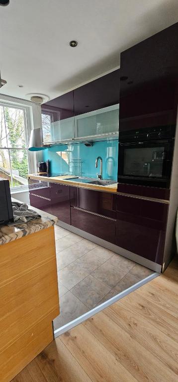 een keuken met bruine kasten en een wastafel bij Highgate Duplex Guest Flat in Londen