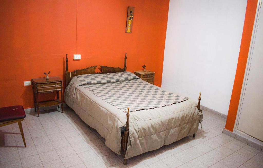 a bedroom with a bed and an orange wall at RHOMBUS HOSPEDAJE Y HABITACIONES in Guaymallen