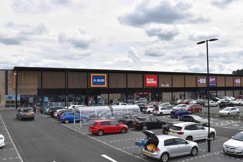 a parking lot with cars parked in front of a building at The Naburn - 3 Bed House with Free Parking & Close to City Centre in Glasgow