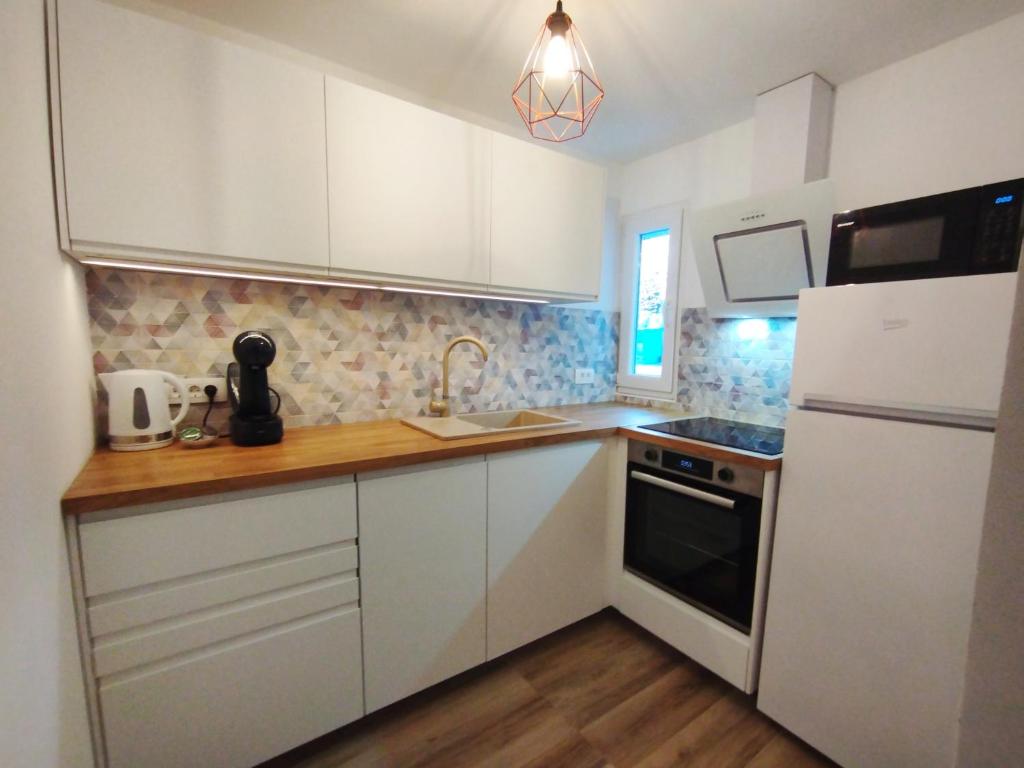 eine Küche mit weißen Schränken, einer Spüle und einem Kühlschrank in der Unterkunft Apartment Ela, Kostrena Rijeka in Kostrena