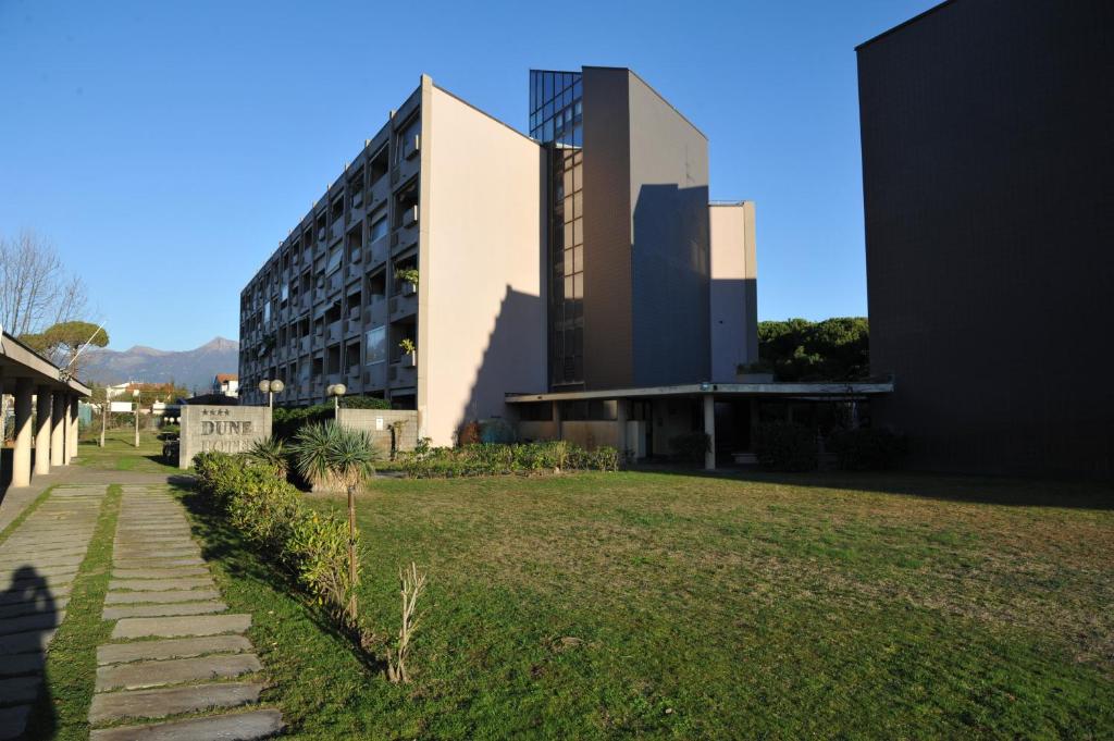 a building with a grass field in front of it at Residence le Dune in Lido di Camaiore