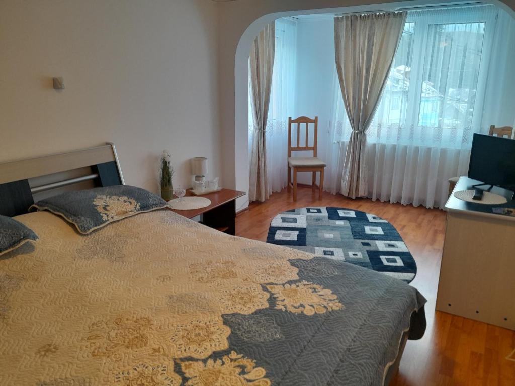 a bedroom with a bed and a desk and a chair at Casa Caldura Rodica in Buşteni
