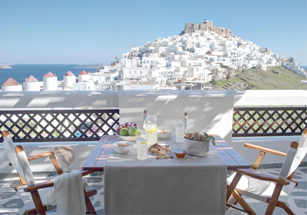 a table on a balcony with a view of a city at Kallichoron Art Boutique Hotel in Astypalaia Town