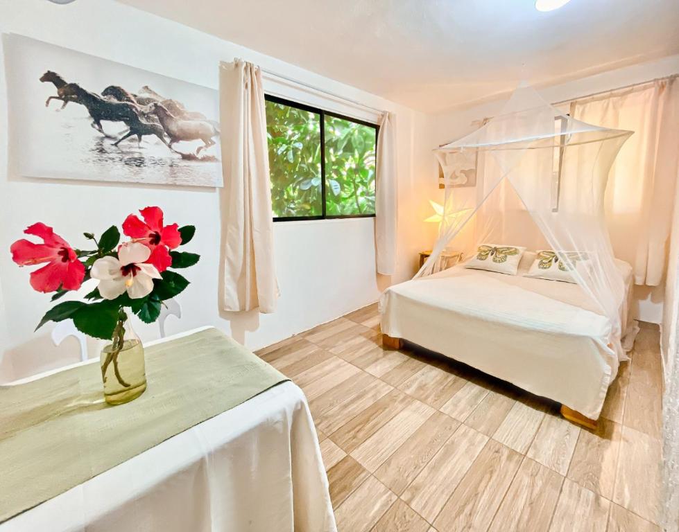 1 dormitorio con 1 cama y un jarrón de flores sobre una mesa en La Hacienda Hostel, en Las Galeras