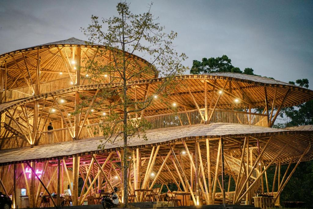 un grand bâtiment en bois avec un arbre en face de celui-ci dans l'établissement The Osing Bamboo Resort - a LIBERTA Collection, à Banyuwangi