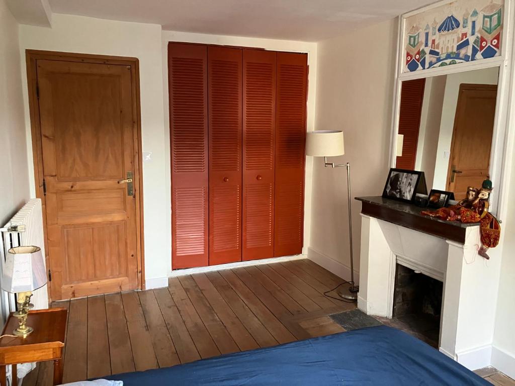 1 dormitorio con 1 cama y chimenea con puerta roja en Chambre d’hôte proche Paris, en Saint-Martin-du-Tertre