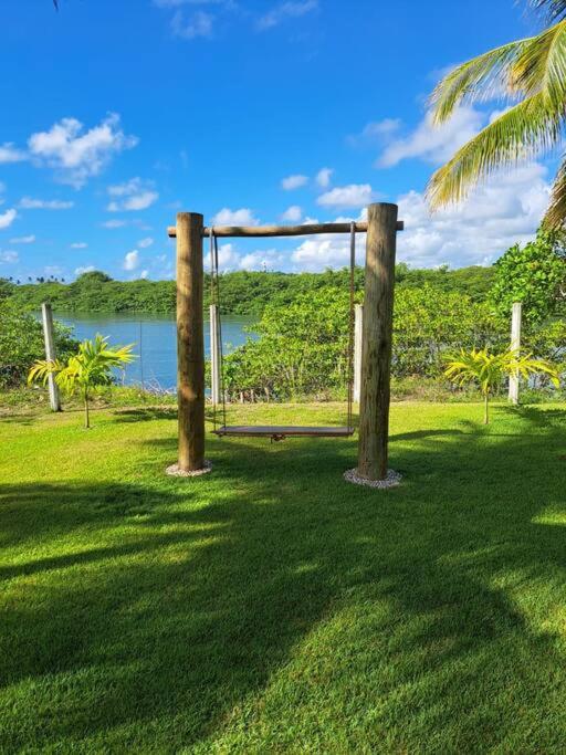 a swing set in a field with a body of water at Paraiso Pasargada in Japaratinga