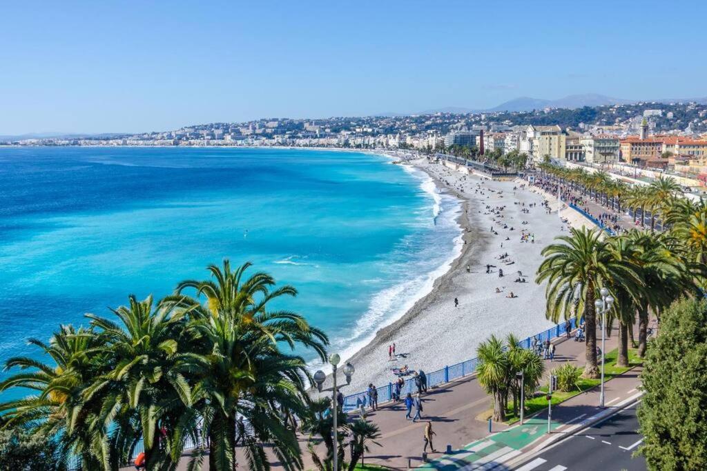 a view of a beach with palm trees and the ocean at « Nice et confortable » 2 pièces cozy in Nice