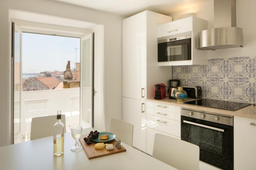 uma cozinha branca com uma mesa e uma janela em Apartamento com varanda no centro de Lisboa, TTL269 em Lisboa
