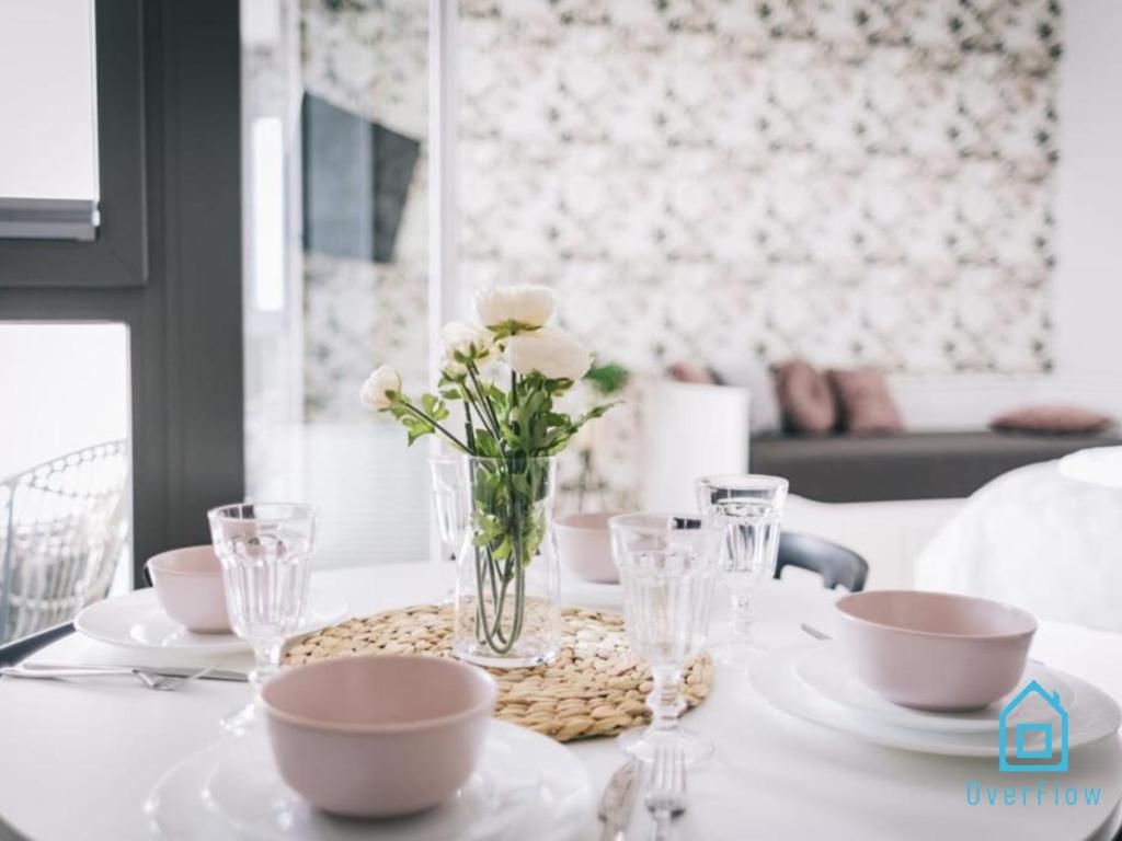 a white table with a vase of flowers on it at White Apartment in Gdańsk