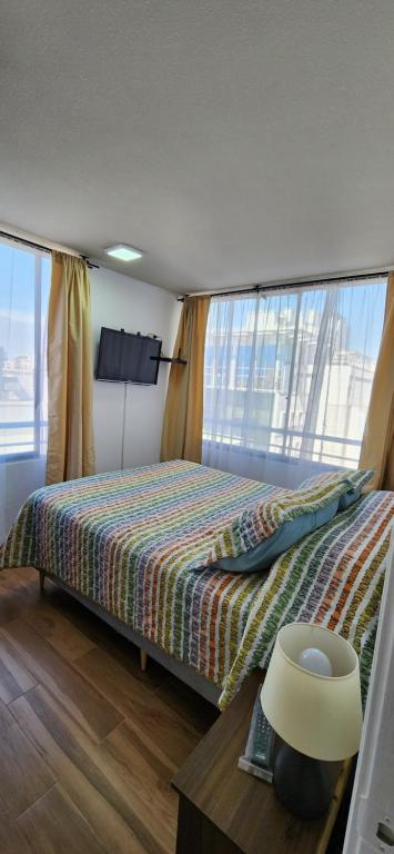 a bedroom with a bed and a table and windows at Personal Aparts Bellas Artes in Santiago