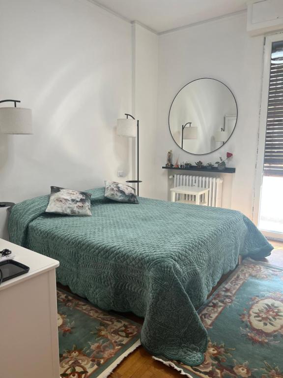 a bedroom with a bed with a green blanket and a mirror at Cucù home in Pisa