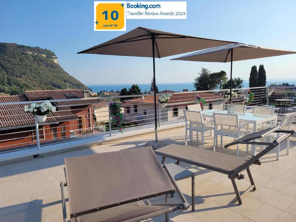 een tafel en stoelen met een parasol op een dak bij Garda view - Nuovo appartamento con solarium vista lago in Garda