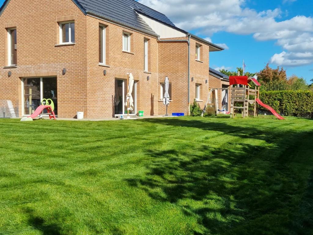 a brick house with a yard with a playground at La maison lumineuse in Hénin-Beaumont