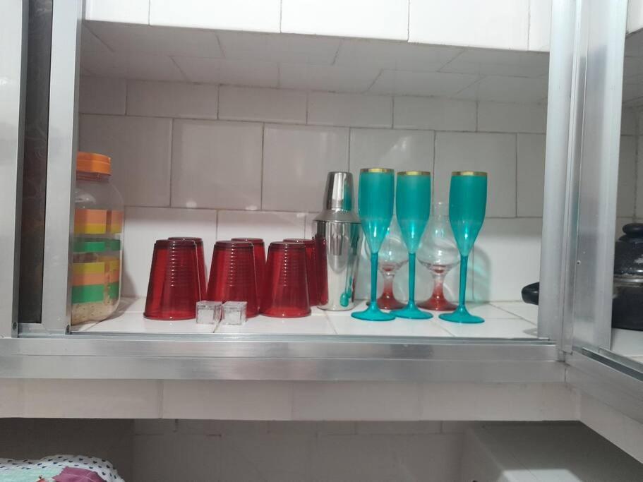 une étagère avec différents vases en verre de couleur sur elle dans l'établissement kit próximo da praia, à Praia Grande