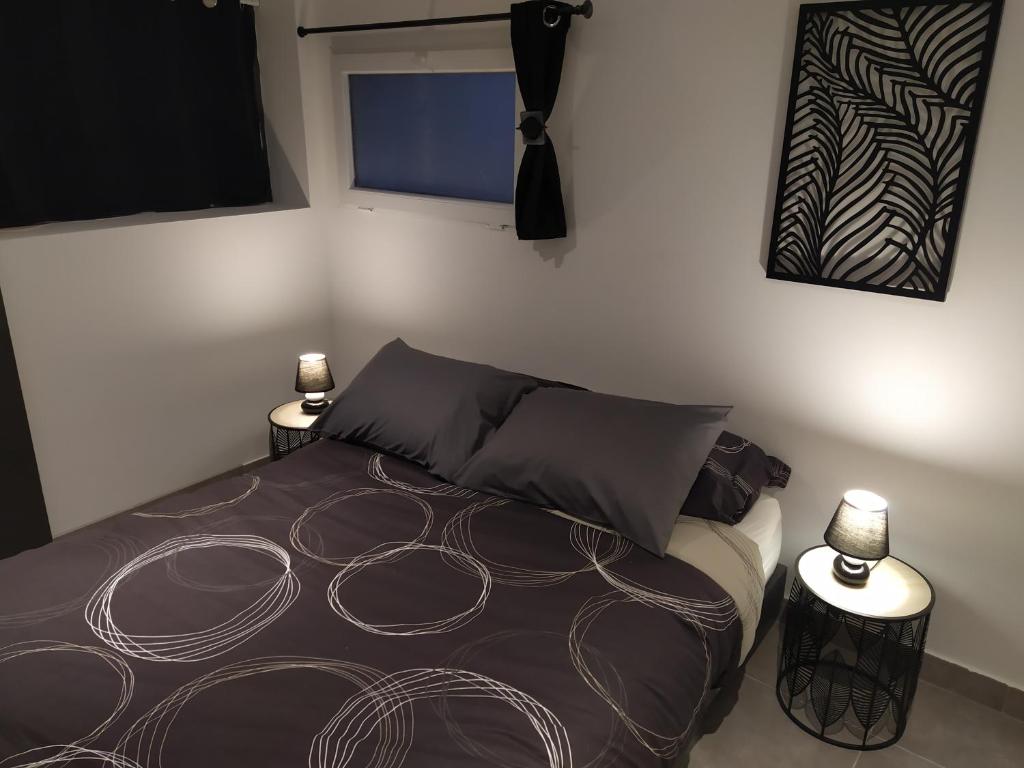 a bedroom with a bed with two lamps on it at charmant gite 25m² indépendant in Alès