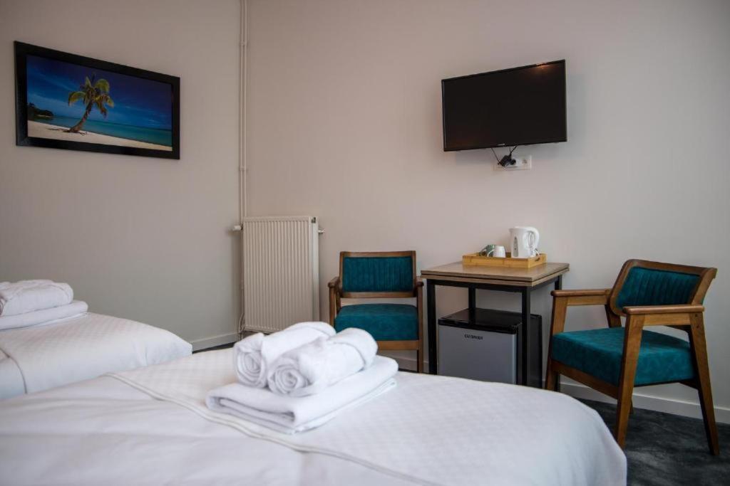 a hotel room with two beds and a desk and a tv at Hotel Guzy in Lier