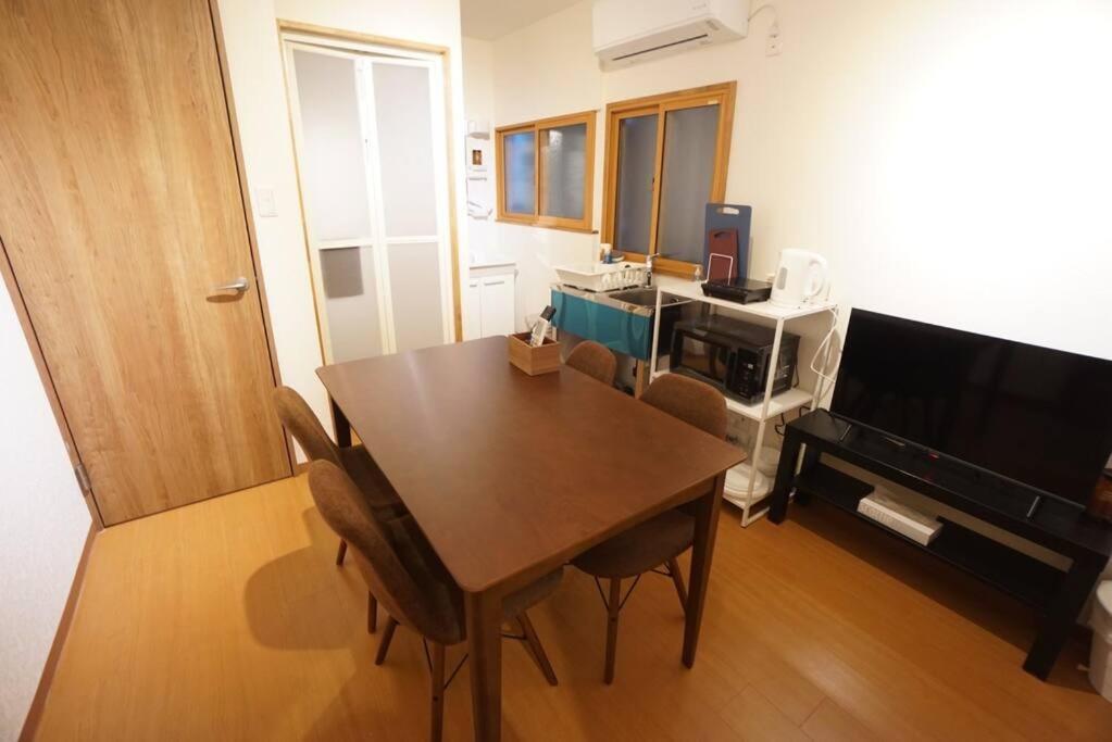 uma sala de estar com uma mesa de madeira e uma televisão em Family Home Shimanouchi House Ⅱ em Osaka