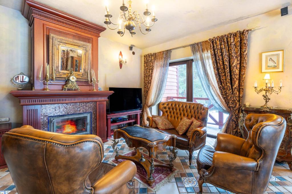 a living room with leather chairs and a fireplace at Nemuno Slėnis in Birštonas