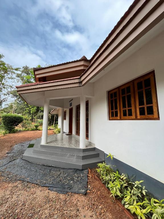 een wit huis met een veranda en een pad bij Puthenveettil in Kottayam