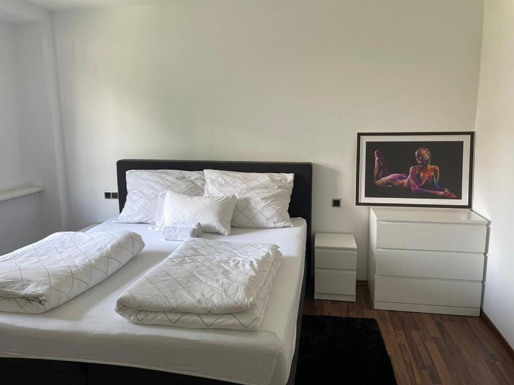 ein Schlafzimmer mit einem weißen Bett und einem Gemälde an der Wand in der Unterkunft Linz Central Apartment in Linz