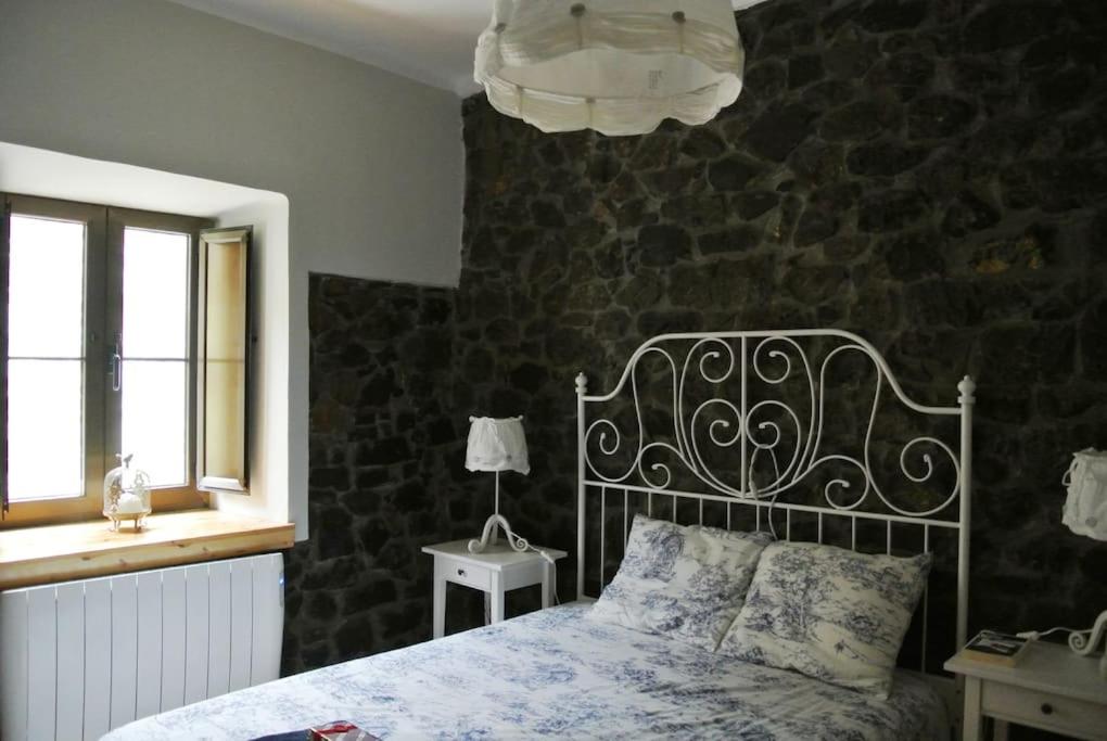 1 dormitorio con cama y pared de piedra en La casa'l cantirín, en Pola de Lena