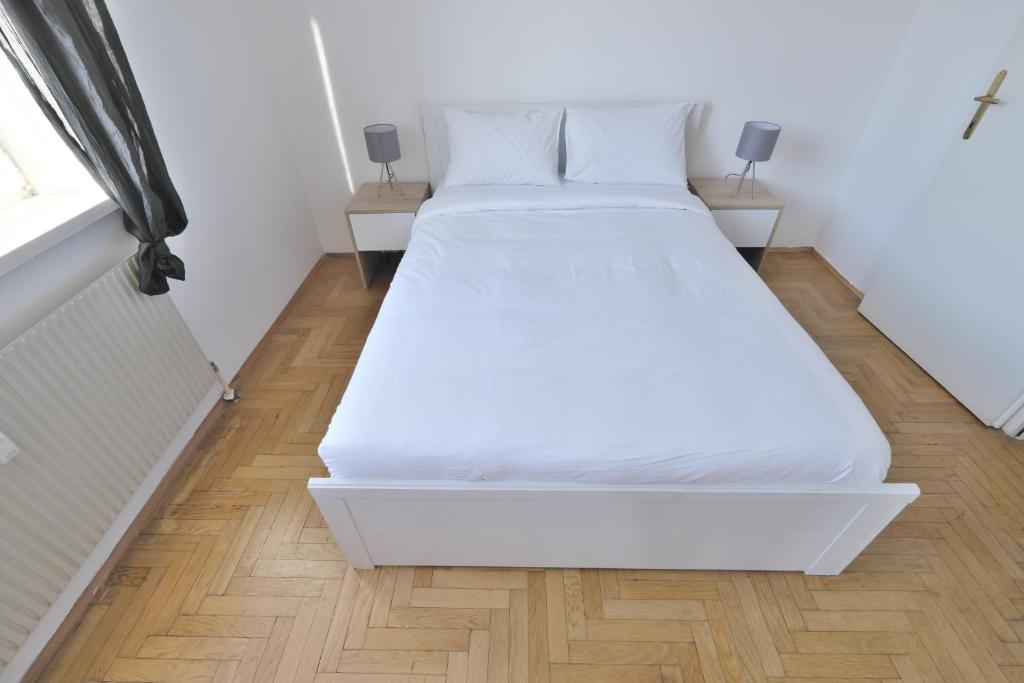 Cama blanca en habitación con suelo de madera en Schönbrunn Apartment en Viena