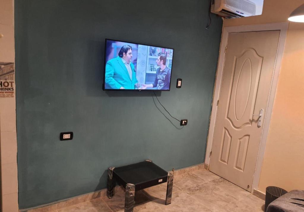 Une télévision à écran plat est installée sur un mur à côté d'une porte. dans l'établissement zooz home vacation, à El Alamein