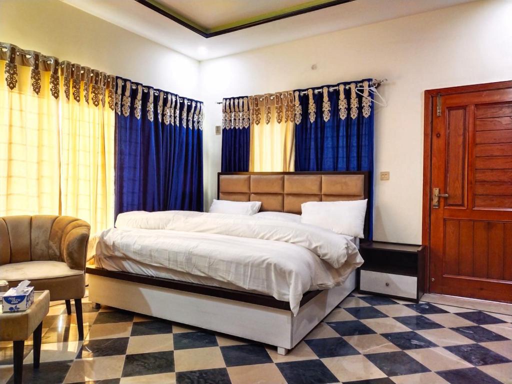 una camera da letto con un letto con tende blu e una sedia di AK House Guest House a Islamabad