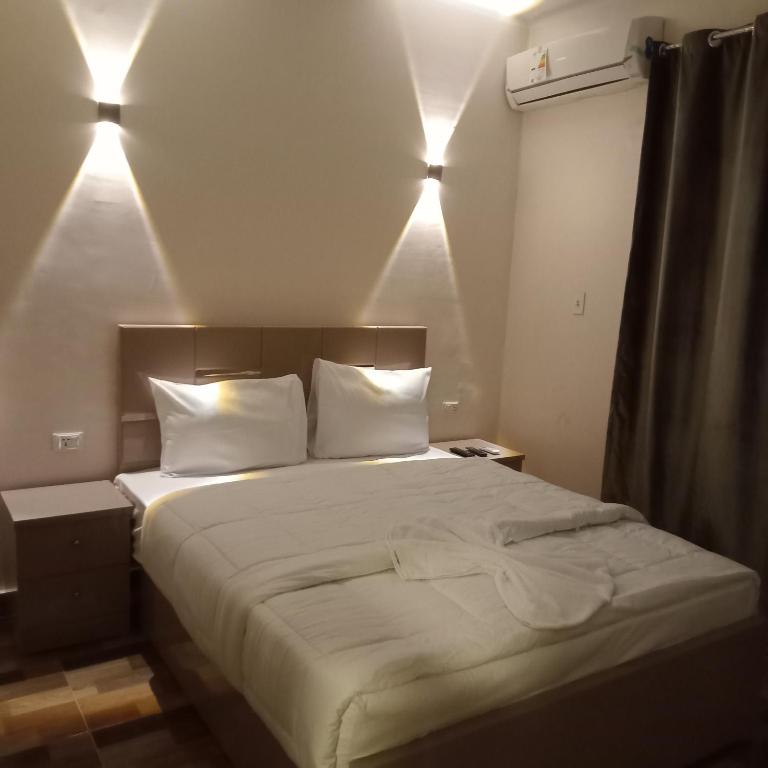 a bed with white sheets and pillows in a room at Cairo de casa hostel in Cairo