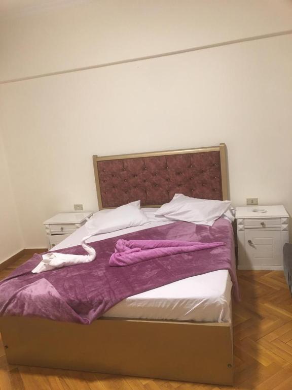 a bed with a purple blanket and two night stands at Cairo de casa hostel in Cairo