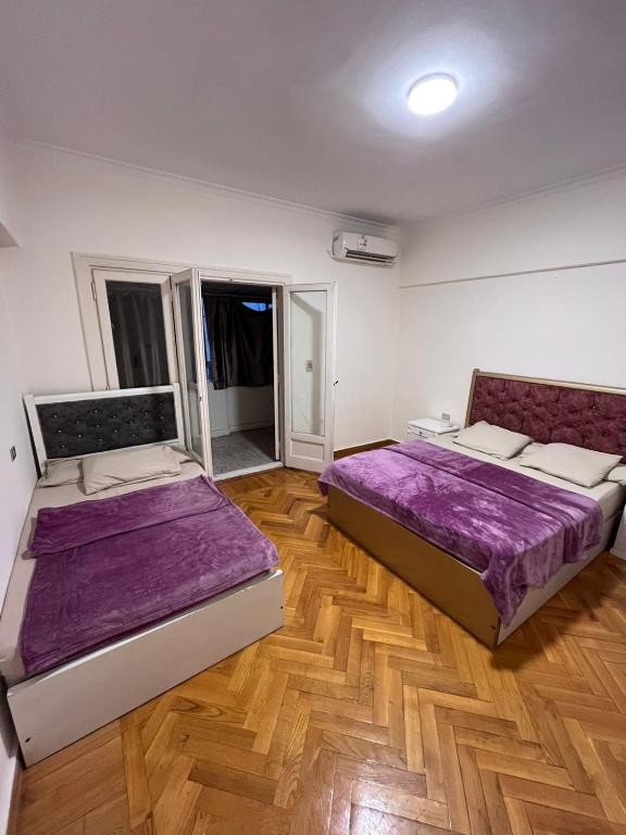 two beds in a room with wooden floors at Cairo de casa hostel in Cairo
