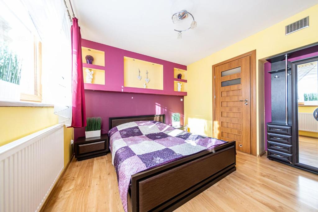 a bedroom with a bed and a purple wall at Topór Apartament rodzinny z kominkiem i placem zabaw Kościelisko Zakopane in Kościelisko