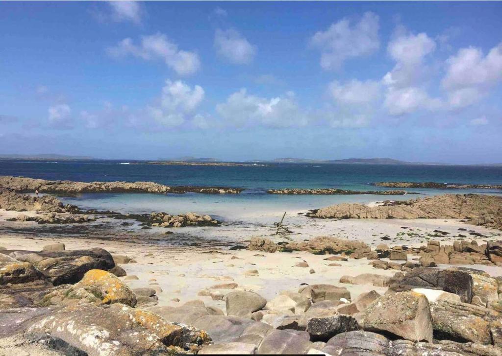 uma praia com pedras e o oceano ao fundo em Drop Anchor Guesthouse em Cleggan