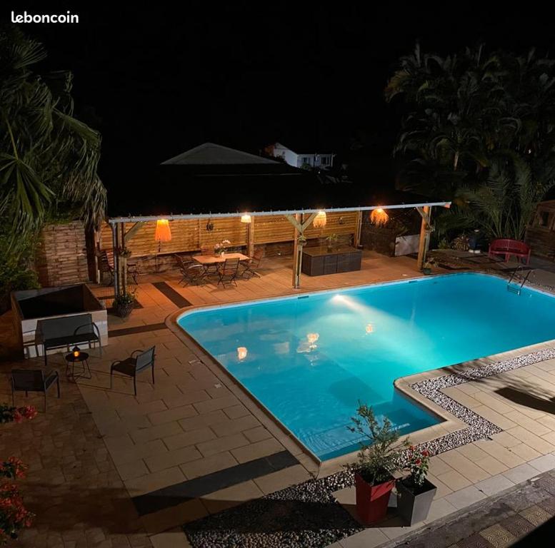 a large blue swimming pool in a yard at night at La Villa d'Elyas in Sainte-Suzanne
