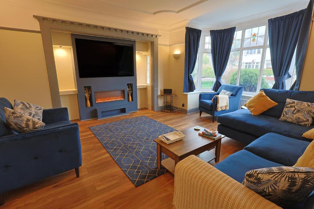 uma sala de estar com sofás azuis e uma televisão em Waves of Memories Rhos on Sea em Llandrillo-yn-Rhôs