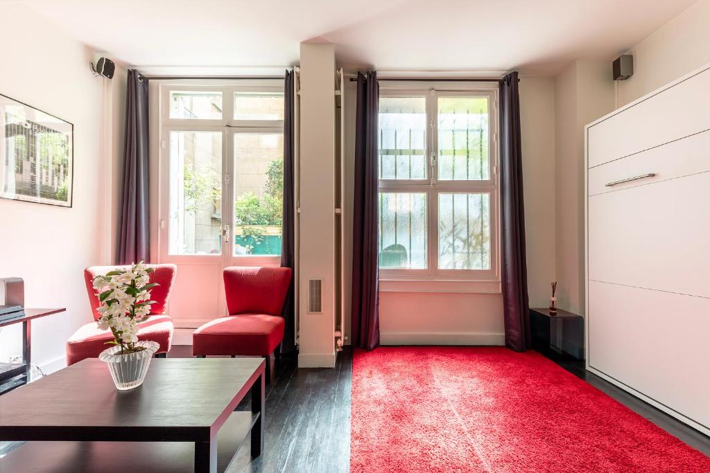 Studio sur les Quais de Seine في باريس: غرفة معيشة مع كراسي حمراء وسجادة حمراء