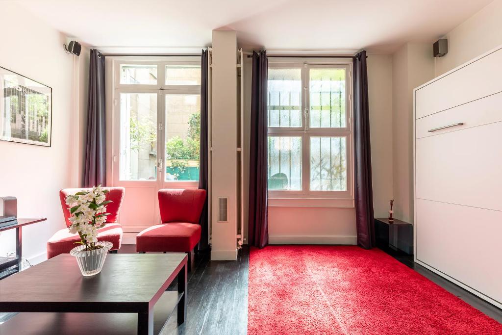 a living room with red chairs and a red rug at Studio sur les Quais de Seine in Paris