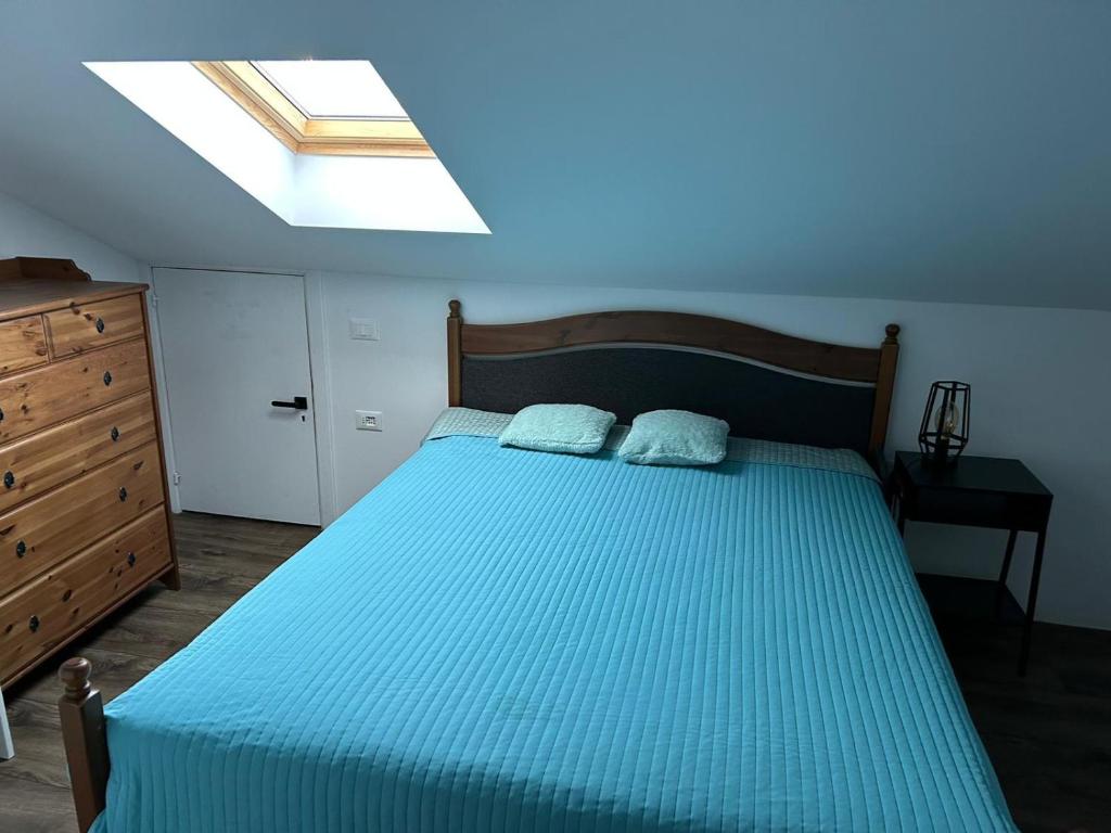 1 dormitorio con 1 cama con sábanas azules y tragaluz en "SALERNO" Apartament w GIFFONI VALLE PIANA dla 6 osób, klimatyzowany, w pełni wyposażony, en Giffoni Valle Piana