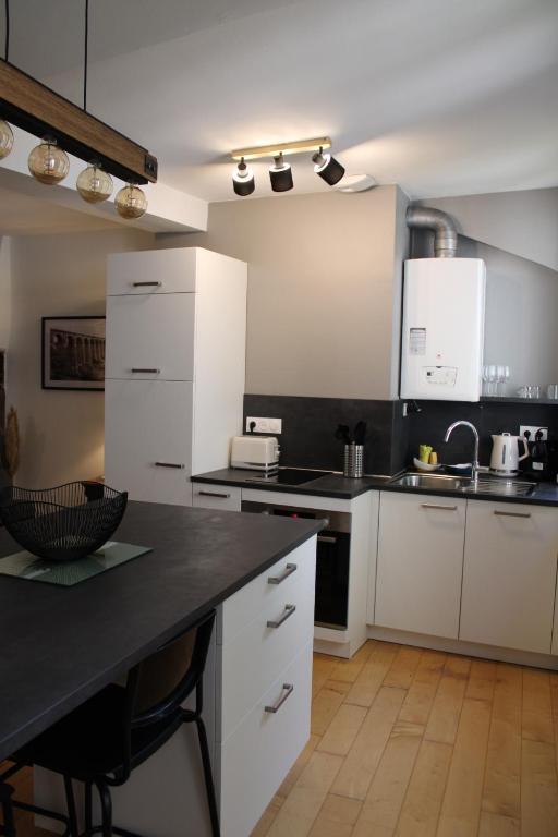 a kitchen with white cabinets and a black counter top at Au Pied du Viaduc in Morlaix