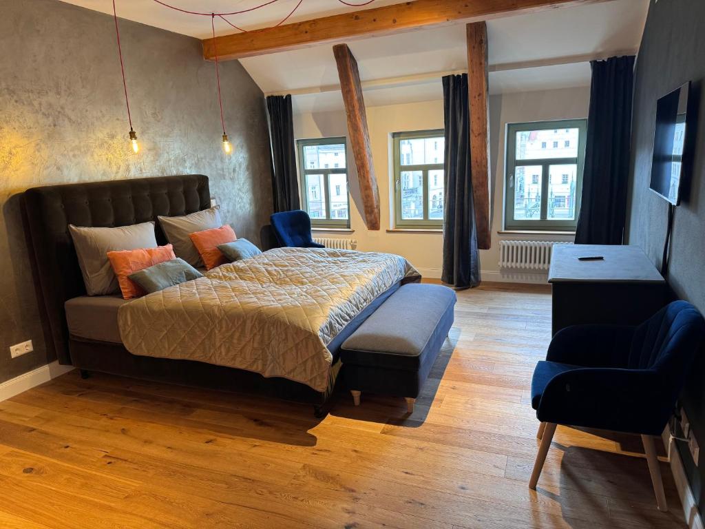 Schlafzimmer mit einem Bett, einem Stuhl und Fenstern in der Unterkunft MARKT LIFE HOME APPARTMENTS in Lutherstadt Wittenberg