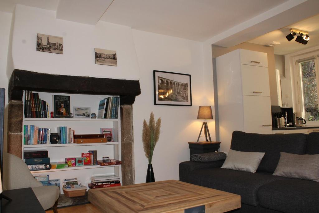 a living room with a couch and a book shelf at Au Pied du Viaduc in Morlaix