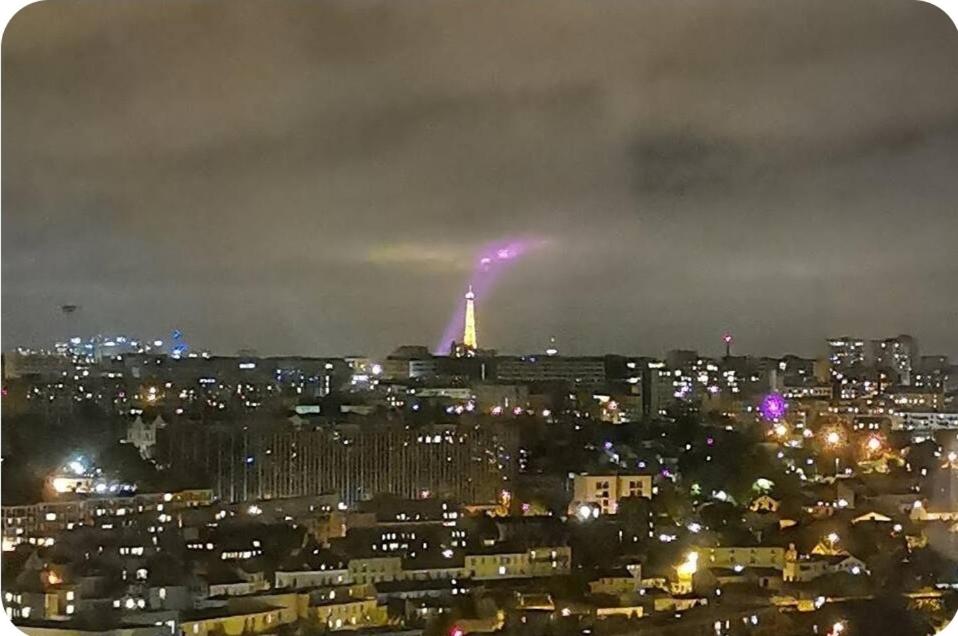 - une vue sur une ville la nuit avec la tour Eiffel dans l'établissement Chambre#1privée en colocation Vue sur Paris Tour Eiffel, à Cachan