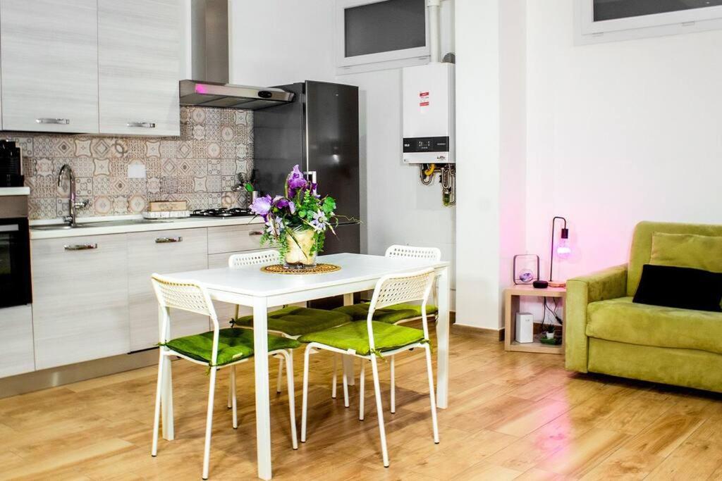 una mesa blanca con sillas y un jarrón de flores en Urban loft - Purple loft en Turín