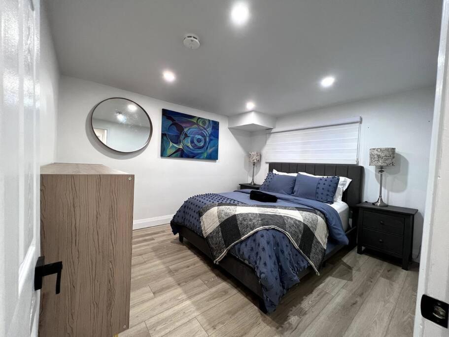 1 dormitorio con cama y espejo en la pared en Long Stay Luxury New Spacious Apartment - Sleeps 6, en Kitchener