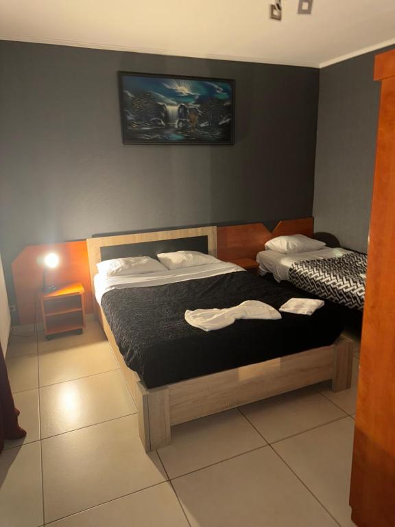 sypialnia z dwoma łóżkami i telewizorem na ścianie w obiekcie Hôtel Rozafa w Charleroi