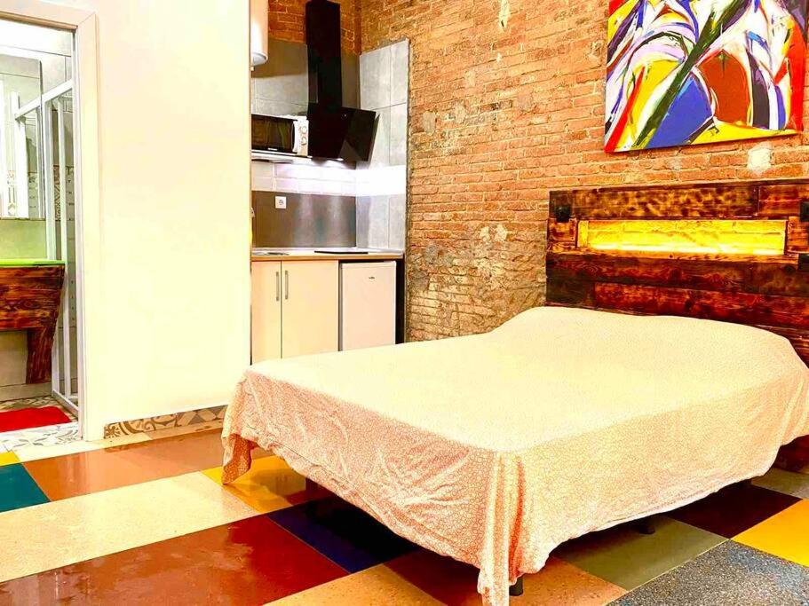 ein Schlafzimmer mit einem Bett in einem Zimmer mit Ziegelwand in der Unterkunft L1 Estudio nuevo! Al lado del metro en Sants in Barcelona